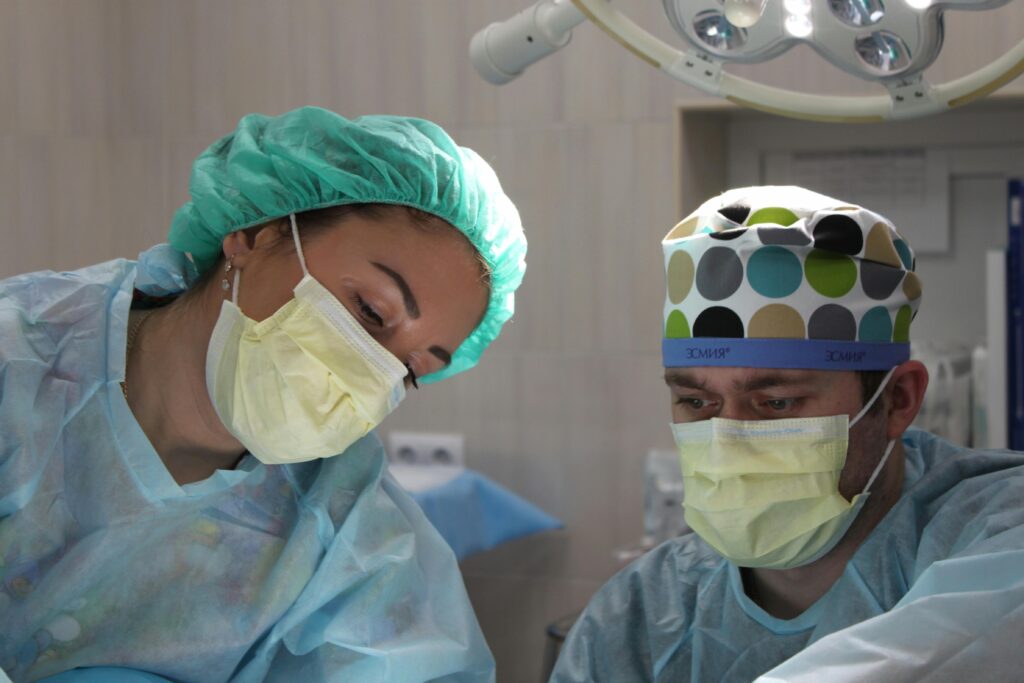 pexels-photo-2324837-2324837 Surgeons wearing masks and scrubs conduct an operation in a hospital setting.
