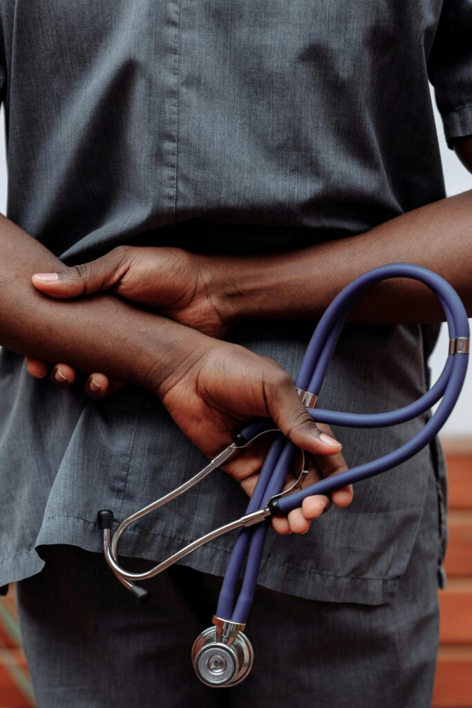 pexels-photo-5327647-5327647 Medical professional in gray scrubs holding stethoscope behind back.